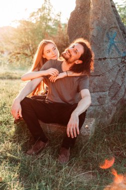 Hippi, romantik çift parkta eğleniyor. Öğleden sonra güneşinin tadını çıkarıyorum. Uzun saçlı kız arkadaşı olan kıvırcık saçlı erkek arkadaş..