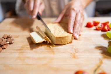 Kadın eli kahvaltıda badem peyniri dilimliyor.
