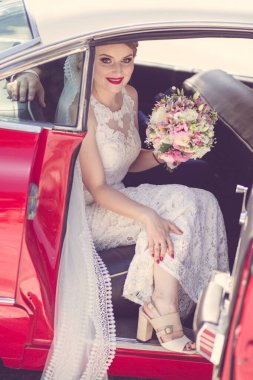 Genç sarışın gelin bir buketle kediden çıkıyor.