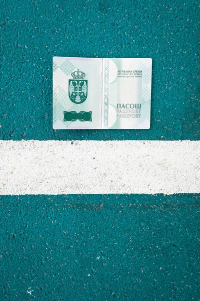 Open national Serbian passport next to a white line on the ground. Symbolic, border