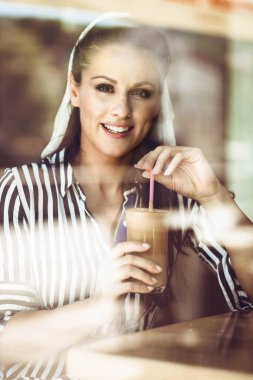 Kafede kahve içen bir kadının portresi. Camdan bak.