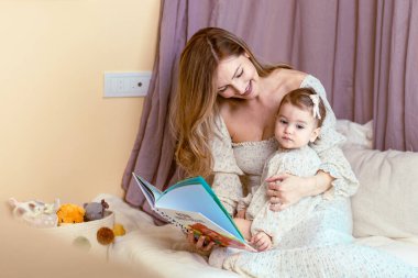 Genç anne kızına kitap okuyor.