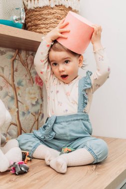 Küçük kız masaya oturmuş kafasına kağıt kova geçiriyordu..