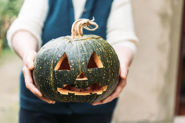 Yaşlı kadın elleri oyulmuş balkabağı tutuyor. Cadılar Bayramı konsepti