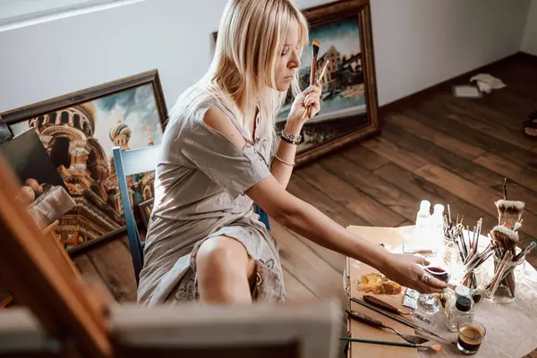 Junge Blonde Malerin Die Ein Glas Wein Vom Tisch Nimmt Stockbild