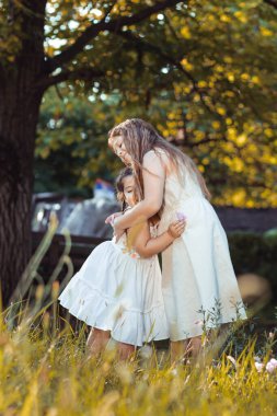 İki küçük kız, beyaz elbiseli kız kardeşler sarılıyorlar.