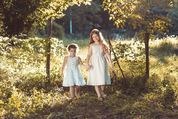 İki küçük kız, beyaz elbiseli kız kardeşler, el ele tutuşuyorlar. Boşluğu kopyala