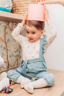 Küçük kız masaya oturmuş kafasına kağıt kova geçiriyordu..