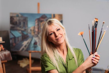 Fırçalı genç sarışın kadın ressam.