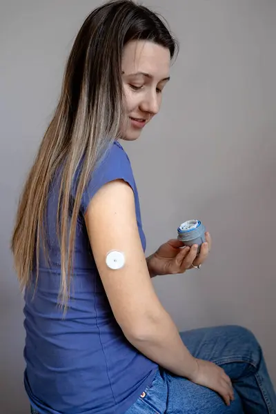 Girl applying flash glucose monitoring patch on her arm