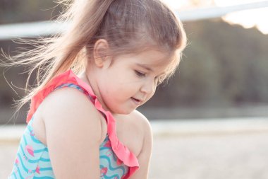 Kumsalda oynayan, mayolu, tatlı, esmer kız.