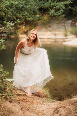 Beyaz elbiseli güzel sarışın kadın dışarıda yürüyor.