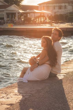 Selanik 'te güneşli bir yaz gününde deniz kenarında oturan genç çift.