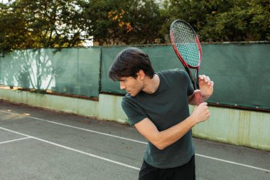 Genç adam tenis oynarken ters vuruş için hazırlanıyor. Boşluğu kopyala