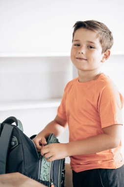 Little school boy preparing schoolbag for school