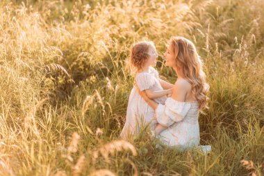 Genç anne kızıyla çimlerin üzerinde oynuyor. Boşluğu kopyala