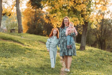 Zencefilli kızları olan genç bir anne. Anneler günü, bağlantı.