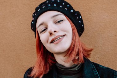 Gülümseyen Kızıl Saçlı Diş telleriyle Kış Giysilerinde Poz Veren Genç Kız