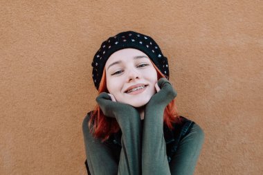 Gülümseyen Kızıl Saçlı Diş telleriyle Kış Giysilerinde Poz Veren Genç Kız