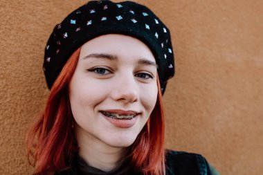 Gülümseyen Kızıl Saçlı Diş telleriyle Kış Giysilerinde Poz Veren Genç Kız