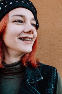 Gülümseyen Kızıl Saçlı Diş telleriyle Kış Giysilerinde Poz Veren Genç Kız