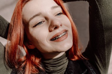 Gülümseyen Kızıl Saçlı Diş telleriyle Kış Giysilerinde Poz Veren Genç Kız