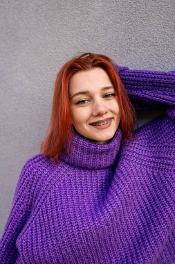 Smiling Redhead Girl with Braces Wearing a Purple Knitted Sweater clipart