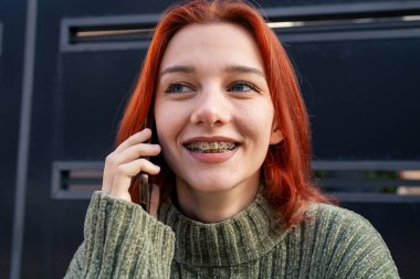 Telefondan konuşan neşeli kızıl saçlı kadın olumlu titreşimler ve iyi haberler.