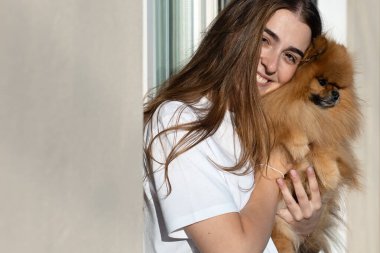 Gülümseyen Genç Kadın Pomeranya Köpeğine Kopya Boşluğu ile sarılıyor