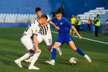SURDULICA, SERBIA, 12 Mart 2025: FK Radnik ve FK Partizan oyuncuları, Sırbistan 'ın Gradski Stadyumu' ndaki SuperLiga futbol karşılaşmasında sıkı bir mücadele içinde görülüyor.