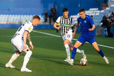 SURDULICA, SERBIA, 12 Mart 2025: FK Radnik ve FK Partizan oyuncuları, Sırbistan 'ın Gradski Stadyumu' ndaki SuperLiga futbol karşılaşmasında sıkı bir mücadele içinde görülüyor.