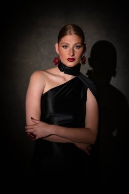 Siyah saten tek omuzlu cüppeli, özgüvenli genç bir kadının orta boy bir portresi. Duruşuyla kameraya bakıyor. Mezuniyet gecesi için hazır..