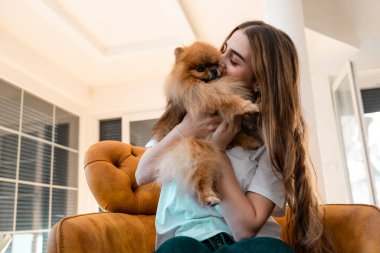 Pomeranian 'ını kucaklayan ve gülümseyen genç bir kadın.