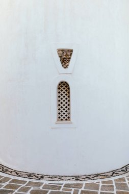 Kavisli beyaz bir duvardaki küçük kavisli pencere, geleneksel Yunan mimarisi
