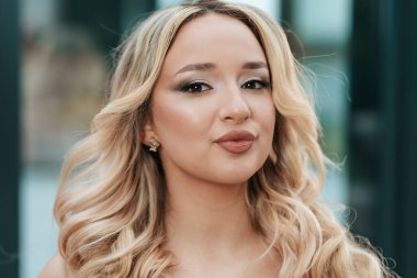 Elegant close-up portrait of a caucasian woman with glamorous makeup and curly blonde hair