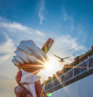 Ice cream cone held up to the hot summer sky in Bournemouth, England