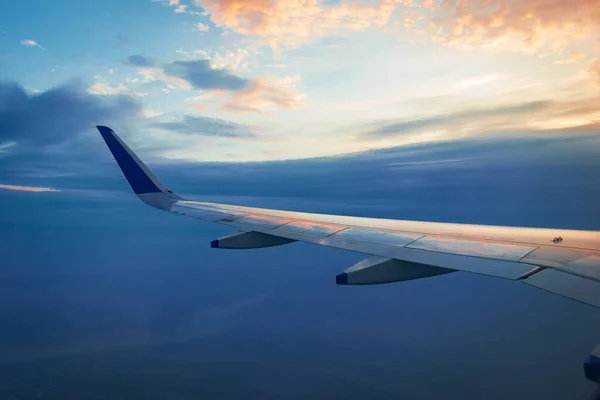 View of plane wing and beautiful sky above the clouds from plane