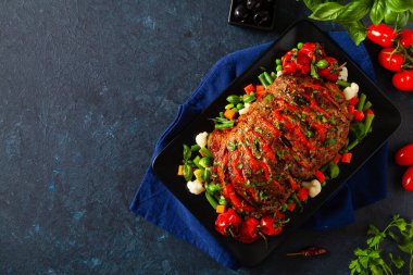 Tam kavrulmuş, domates, zeytin ve domuz boynuyla doldurulmuş. Karanlık arka plan, karanlık ruh hali.