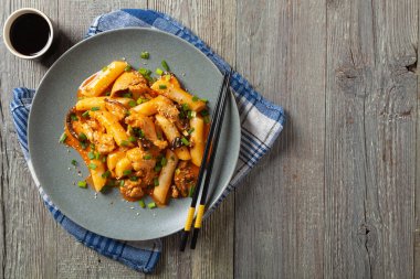 Geleneksel Kore Tteokbokki pilavı, tavuk, sebze ve mantarlı erişte. Tavada hazır. Ahşap arka plan. Üst görünüm.