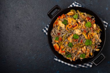 Siyah susamlı buğday eriştesi, tavuk ve sebzeli tavada kızartılmış. Üst görünüm.