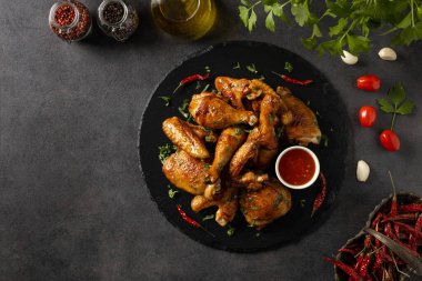 Fırında tavuk parçaları karışımı. Acı sos ya da patates kızartması ile servis edilir. Koyu arkaplan.