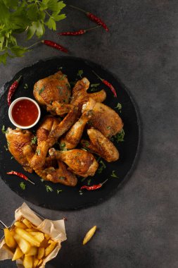 Fırında tavuk parçaları karışımı. Acı sos ya da patates kızartması ile servis edilir. Koyu arkaplan.