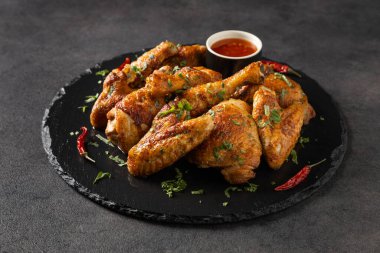 Fırında tavuk parçaları karışımı. Acı sos ya da patates kızartması ile servis edilir. Koyu arkaplan.