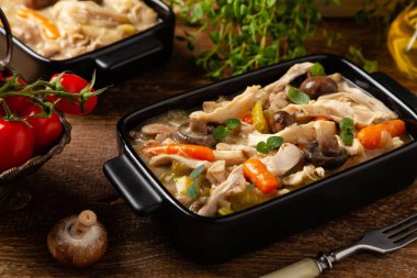 Geleneksel mantar ve sebzeli tavuk güveci. Tavuk güveci. Siyah kaplarda servis edilir..