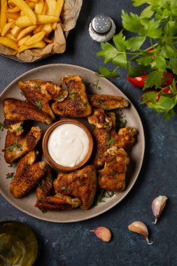 Fırında tavuk kanadı. Sos ya da patates kızartması ile servis edilir. Koyu arkaplan.