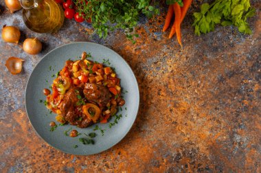 Ossobuco haşlanmış sebzelerle servis edilir. Renkli bir geçmiş. Gri tabak.