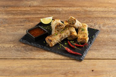 Etle doldurulmuş börekler. Sos ile servis edilir. Doğal ahşap arkaplan.