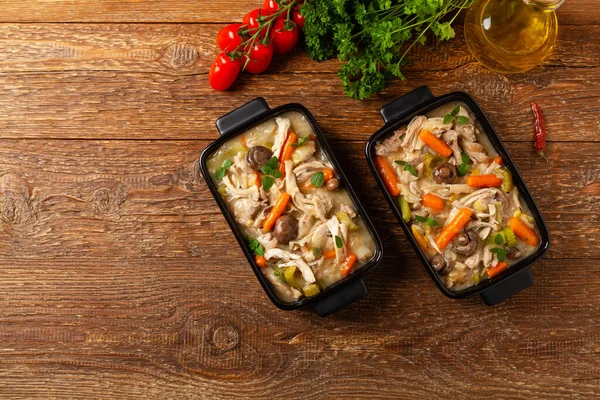 Traditional chicken stew with mushrooms and vegetables. Chicken casserole. Served in black pots.
