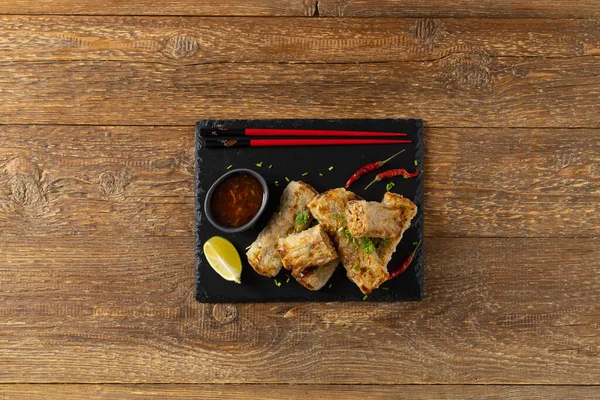 Etle doldurulmuş börekler. Sos ile servis edilir. Doğal ahşap arkaplan.