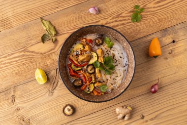 Tavuk, biber ve mantarlı Tayland çorbası. Hindistan cevizi sütüyle birlikte. Klasik bir Asya kâsesinde servis edilmiş. Arka planda doğal ahşap..